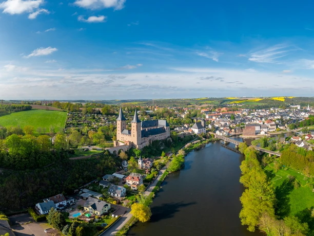 Ujęcie z drona Zwickauer Mulde z imponującym zamkiem Rochlitz i mostem wiszącym w pobliżu Zaßnitz wiosną z żółtymi polami rzepaku w oddali, Mulde Cycle Path, Luther Trail Saxony