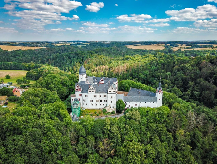 Schloss Rochsburg - Schlösser der Leipzig Region Vogelperspektive auf Schloss Rochsburg umgeben von grünen Wäldern und Feldern in der Ferne, Ausflugsziel, WandernBird's eye view of Rochsburg Castle surrounded by green forests and fields in the distance, excursion destination, hikingPohled z ptačí perspektivy na hrad Rochsburg obklopený zelenými lesy a poli v dálce, výletní cíl, pěší turistikaZamek Rochsburg z lotu ptaka otoczony zielonymi lasami i polami w oddali, cel wycieczek, turystyka pieszaVogelperspectief op kasteel Rochsburg omringd door groene bossen en velden in de verte, excursiebestemming, wandelenVista a volo d'uccello del castello di Rochsburg circondato da verdi boschi e campi in lontananza, meta di escursioni, trekking