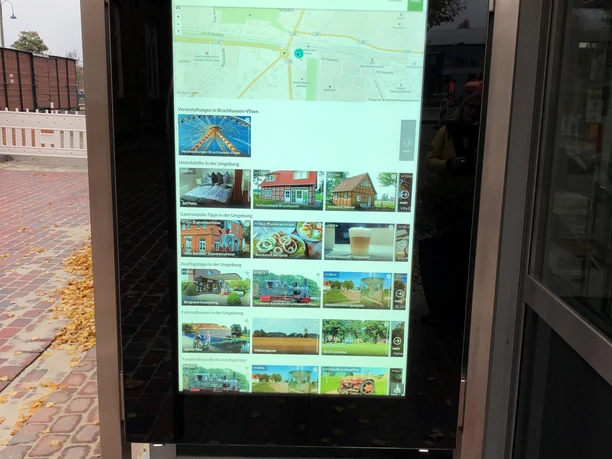 Information kiosk in Bruchhausen-Vilsen, located on the sidewalk, featuring an electronic touchscreen and a map of the area.