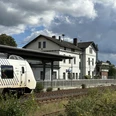 Am Bahnhof Ein moderner Zug hält an einem kleinen, ländlichen Bahnhof unter einem bewölkten Himmel.