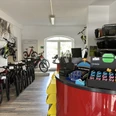 Bikers Point Fahrradladen mit verschiedenen Fahrrädern und Zubehör auf hölzernem Boden, freundlich beleuchtet.