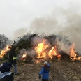 Osterfeuer Backemoor Großes, rauchendes Osterfeuer auf einem Feld. Im Vordergrund betrachten Menschen die Flammen.