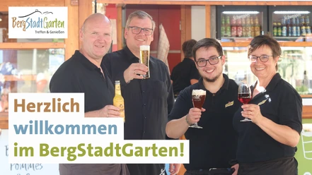 BergStadtGarten_Willkommen5.jpg Vier Personen in schwarzer Kleidung stoßen im BergStadtGarten mit verschiedenen Getränken an.