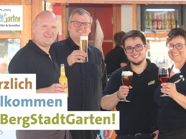 BergStadtGarten_Willkommen5.jpg Vier Personen in schwarzer Kleidung stoßen im BergStadtGarten mit verschiedenen Getränken an.