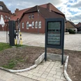 Infoterminal Rehburg Infoterminal vor roten Backsteingebäuden mit Kopfsteinpflaster und Fahrradzubehör auf einem Platz.