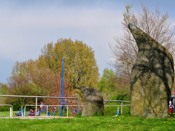 Abenteuerspielplatz (c) Suermann, Marienmünster.JPG Ein Abenteuerspielplatz mit Klettergerüst, Felsen im Vordergrund und spielenden Kindern im Hintergrund.