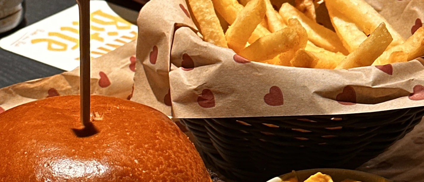 Burgerheart in Monheim Mitte Ein Burger mit Salat, einer Portion Pommes frites und Käsesauce in einem Restaurant.