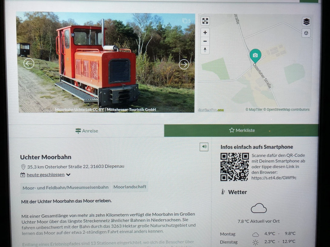 Infoterminal Diepenau Ein moderner Infoterminal zeigt die Uchter Moorbahn, eine historische kleine rote Lokomotive.
