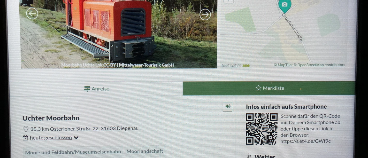 Infoterminal Diepenau Ein moderner Infoterminal zeigt die Uchter Moorbahn, eine historische kleine rote Lokomotive.