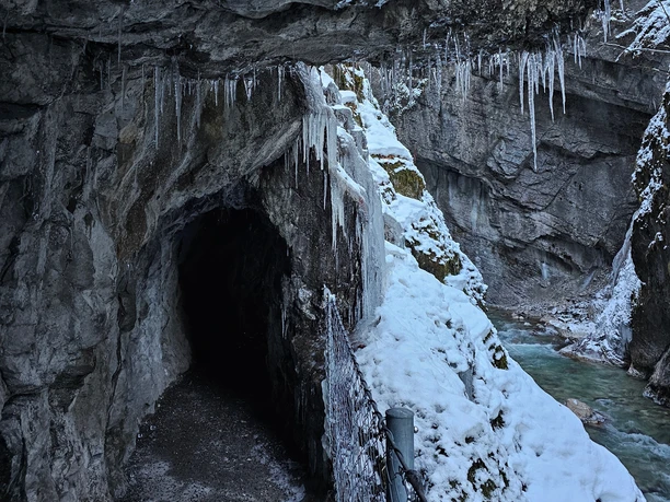 Partnachklamm im Winter Vereister Felstunnel mit herabhängenden Eiszapfen über einem winterlichen Bach