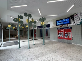 Bahnhofsfoyer Offenes Bahnhofsfoyer mit Fahrkartenautomaten, digitalen Anzeigetafeln und modernen Designelementen.