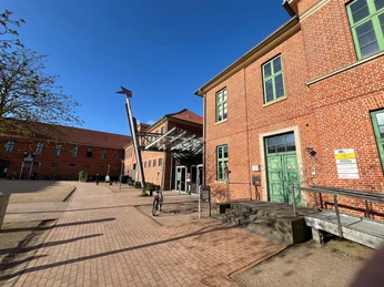 Roter Backsteinbau der Stadthalle Verden mit modernem Eingang und ausfahrendem Glasdach.