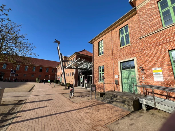 Roter Backsteinbau der Stadthalle Verden mit modernem Eingang und ausfahrendem Glasdach.