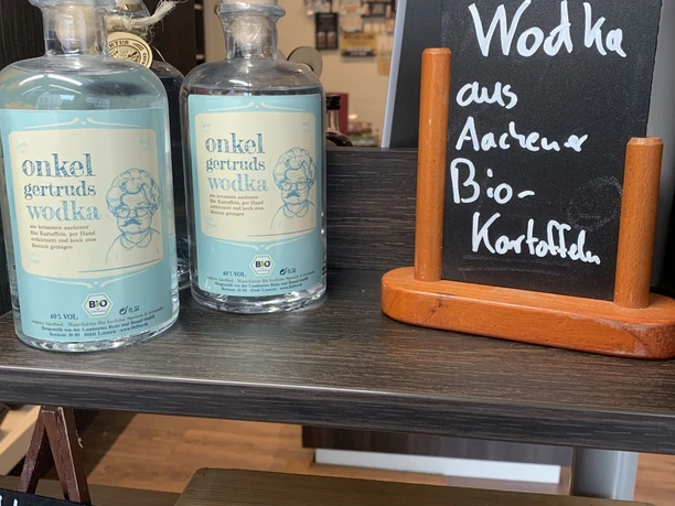 Auf einem Tisch stehen zwei Flaschen mit blauem Etikett, auf dem "onkel gertruds wodka" steht sowie eine kleine Kreidetafel daneben.