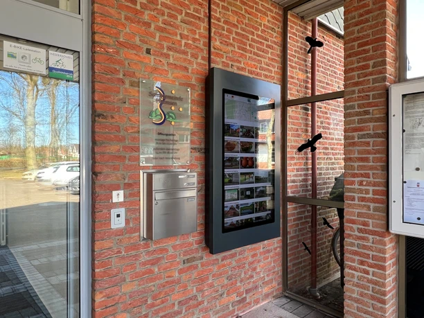 An information kiosk against a red brick wall, providing information about local attractions in Heemsen.