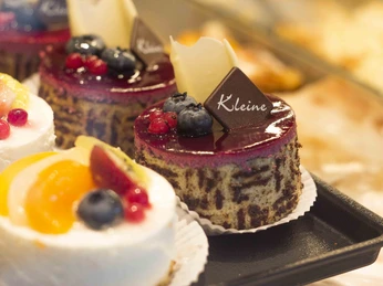 Cafe Kleine Herford (2).jpg Ein Teller mit verschiedenen verzierten Törtchen, dekoriert mit frischen Beeren und Schokolade.