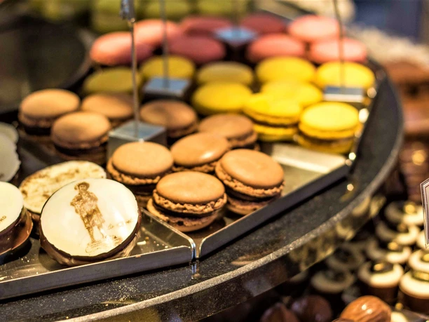 Verschiedene bunte Macarons und Pralinen auf einem Tablett in einem Café, verlockend arrangiert.