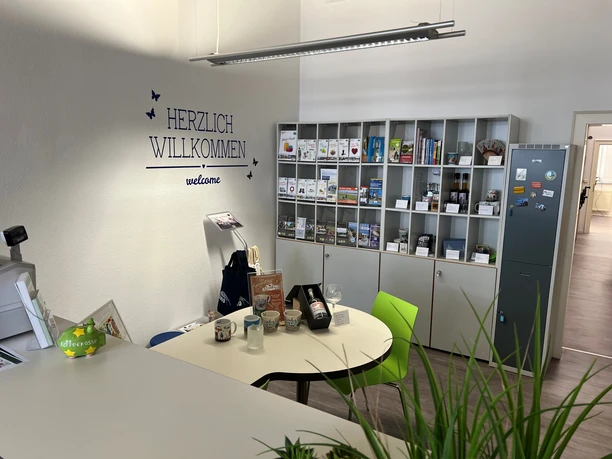 Bright room of the Nienburg Tourist Information Office with information counter, flyers and bookshelf in the background.