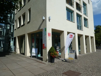 Tourist Information Achim on a sunny day with information banner and shop windows.