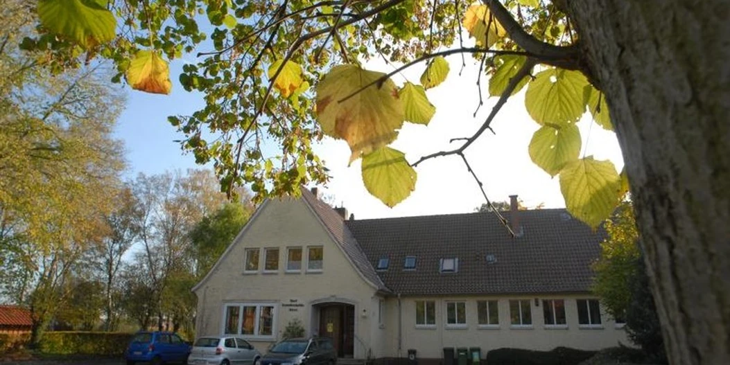 Dorfgemeinschaftshaus in Alt-Espelkamp Das Dorfgemeinschaftshaus Alt-Espelkamp mit gelben Herbstblättern im Vordergrund auf einem Baumzweig.