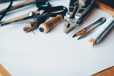 Repair Café CASA Auf dem Bild liegen Werkzeuge wie eine Schere, eine Zange und Bleistifte auf einem Tisch.