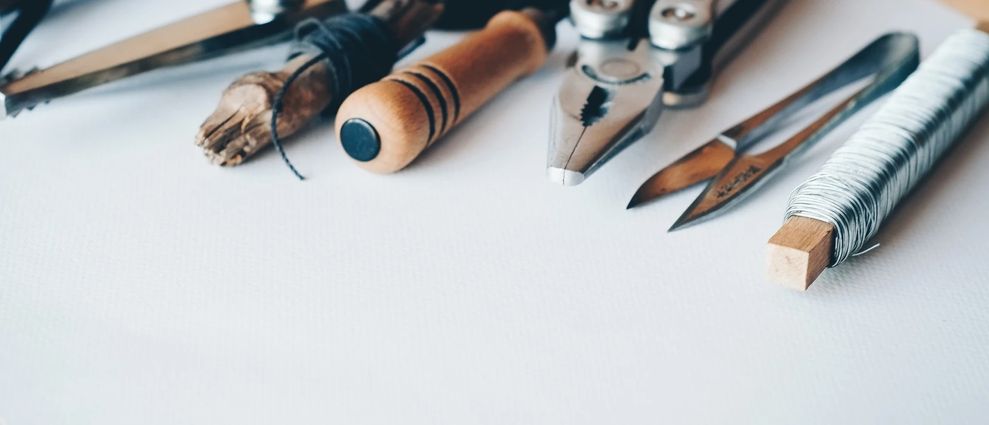 Repair Café CASA Auf dem Bild liegen Werkzeuge wie eine Schere, eine Zange und Bleistifte auf einem Tisch.