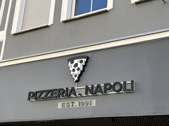 Herford-Pizzaria Napoli-Pro Herford GmbH (81).jpeg Fassade der Pizzeria Napoli mit einem Pizza-Symbol und dem Gründungsjahr 1991 darüber.