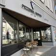 Herford-Pizzaria Napoli-Pro Herford GmbH (85).jpeg Pizzeria mit Außenterrasse, Holztischen und Stühlen, gelegen an einer Straßenecke, lädt zum Verweilen.