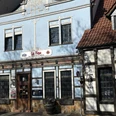 Herford-Le Feu-Pro Herford GmbH (27).jpeg Historisches Gebäude mit blauem Fachwerk; Restaurant Le Feu in Herford, Sonnenlicht beleuchtet die Fassade.