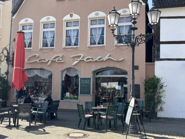 Café Jach mit rotem Sonnenschirm und Außensitzbereich, historische Hausfassade und Straßenlaternen.