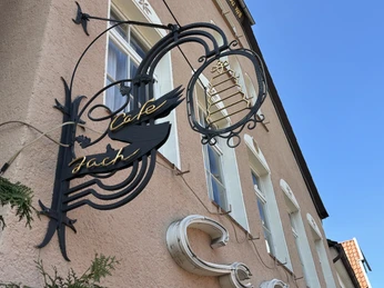 Herford-Café Jach-Pro Herford GmbH (74).jpeg Fassade eines historischen Gebäudes mit kunstvollem "Café Jach"-Schild und blauen Himmel.