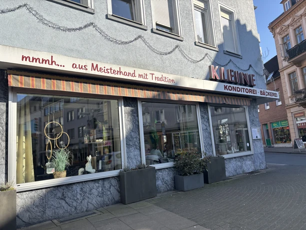 Außenansicht eines Konditorei-Cafés mit großen Schaufenstern und traditioneller Beschilderung.