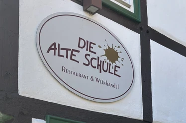 Herford-Die Alte Schule-Pro Herford GmbH (21).jpeg Das Schild der "Die Alte Schule" in Herford, ein Restaurant und Weinhandel, an Fachwerk.
