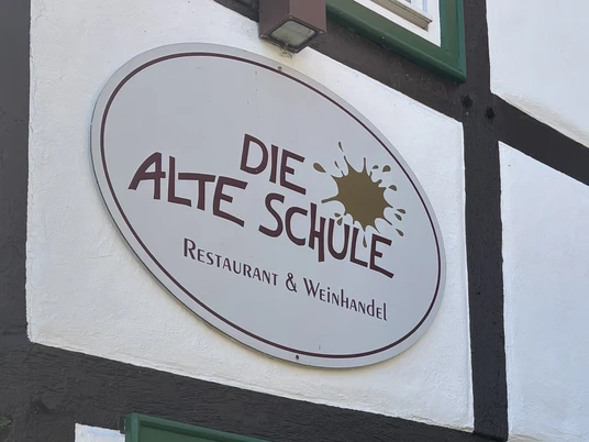 Herford-Die Alte Schule-Pro Herford GmbH (21).jpeg Das Schild der "Die Alte Schule" in Herford, ein Restaurant und Weinhandel, an Fachwerk.