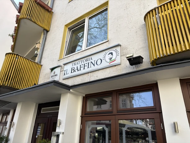Herford-Trattoria il Baffino-Pro Herford GmbH (76).jpeg Gelbes, mehrstöckiges Gebäude mit dem Schild der Trattoria "Il Baffino" und großen Fenstern.