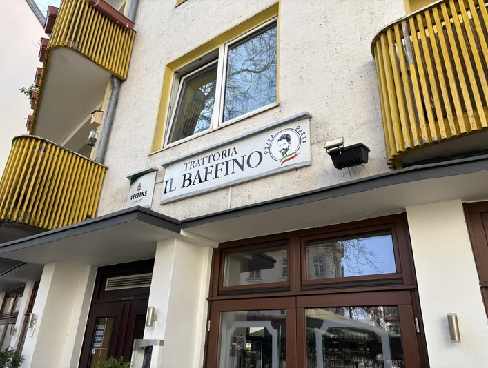 Herford-Trattoria il Baffino-Pro Herford GmbH (76).jpeg Gelbes, mehrstöckiges Gebäude mit dem Schild der Trattoria "Il Baffino" und großen Fenstern.