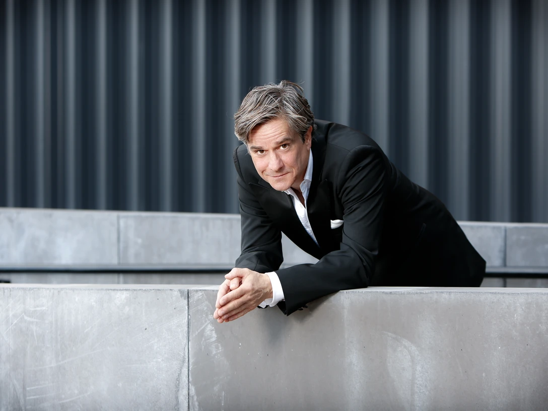 Juliano Rossi von Nadja Mahjoub.jpg Sänger Juliano Rossi lehnt an einer Betonmauer, in elegantem Anzug vor modernem Hintergrund.