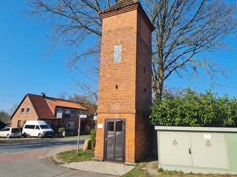 Trafoturm Brokeloh Backstein-Trafoturm in Brokeloh an einer Straße. Gebäude umgeben von Bäumen und blauen Himmel.