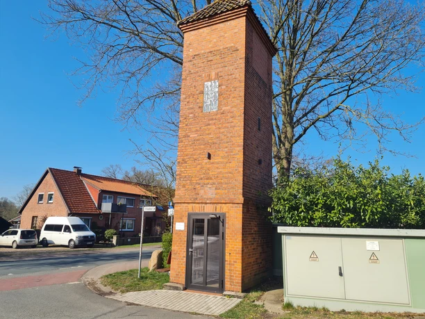 Trafoturm Brokeloh Backstein-Trafoturm in Brokeloh an einer Straße. Gebäude umgeben von Bäumen und blauen Himmel.