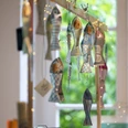 Papier- und Fairmarkt Dekorative Papierfische und Lichterketten hängen an einem Holzgestell vor einem Fenster mit grünem Ausblick.