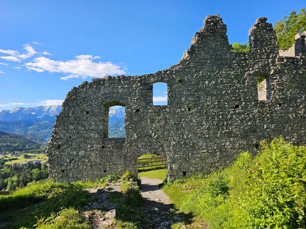 Burgruine Werdenfels Steinerne Burgruine mit geöffnetem Bogen und Blick auf grüne Täler und schneebedeckte Berge.