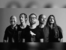 Fünf musizierende Männer in monochrom, frontal in entspannter Pose, mit unterschiedlichen Gesichtsausdrücken.