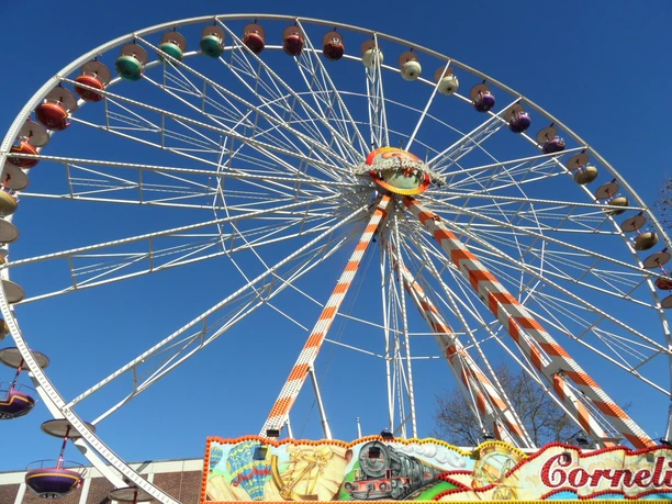 Volksfest auf der Freiheit - Pro Herford GmbH.JPG Riesenrad auf einem Volksfest vor blauem Himmel, bunte Gondeln und dekorative Details.