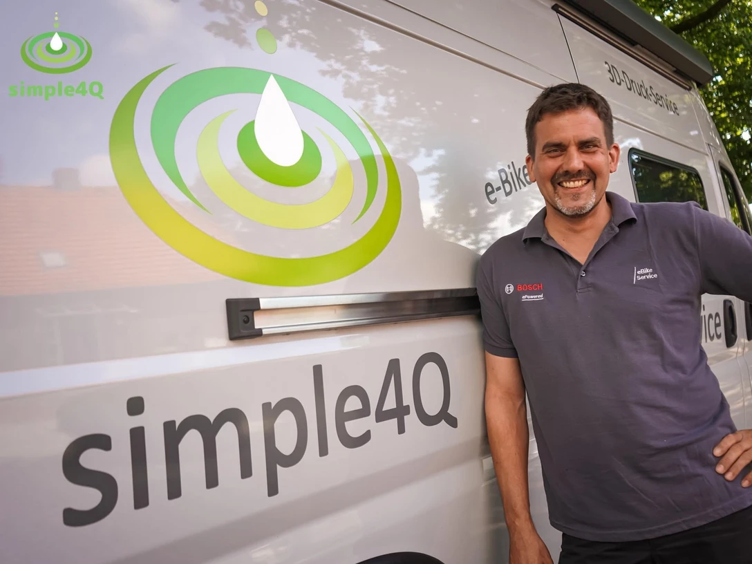 simple4Q.jpg Ein lächelnder Mann lehnt an einem weißen Van mit dem Logo "simple4Q".
