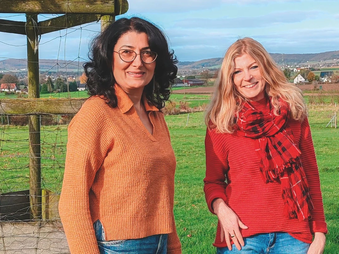 Ruzanna Shahinyan + Silke Domke.jpg Zwei Frauen, eine mit schwarzen Haaren und eine mit blonden, stehen lächelnd auf einer Wiese.