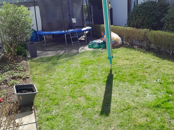 Ferienwohnung Preyersmühle Ein grüner Garten mit Trampolin, Wäscheständer und Hecken, umgeben von Wohnhäusern und Bäumen.