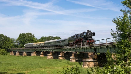 A steam train crosses the railroad bridge in Kössern on its summer journey through the Leipzig region