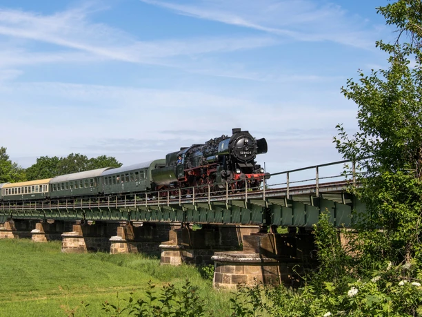 A steam train crosses the railroad bridge in Kössern on its summer journey through the Leipzig region