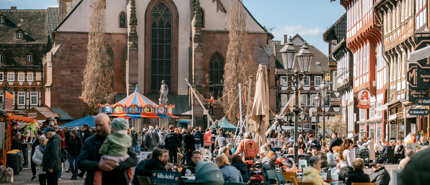 Frühjahrsmarkt Belebter Frühjahrsmarkt vor Kirche mit Karussell, Ständen und vielen Besucher:innen.