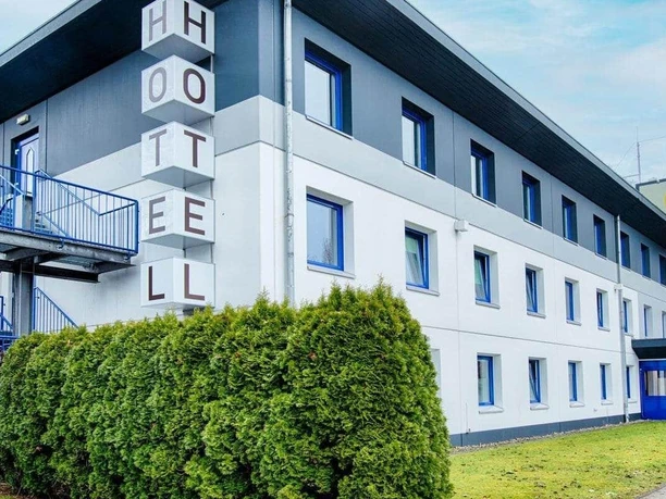 Ein modernes Hotelgebäude mit einem klaren Design. Die Außenanlage ist gepflegt und lädt zum Verweilen ein.